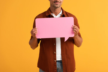 cropped view of happy man holding pink speech bubble isolated on orange