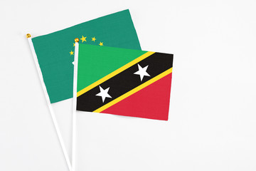 Saint Kitts And Nevis and Macao stick flags on white background. High quality fabric, miniature national flag. Peaceful global concept.White floor for copy space.