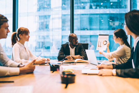 Woman showing document with statistics to coworkers