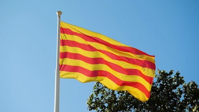 Flag of Catalonia waving in wind against sky. Barcelona. Spain. Slow motion. HD
