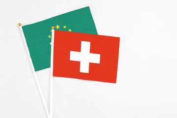 Obraz premium Switzerland and Macao stick flags on white background. High quality fabric, miniature national flag. Peaceful global concept.White floor for copy space.