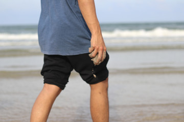 Close up of Men's hand hold sand of Young men in front of the sea and beach