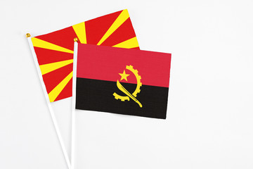 Angola and Macedonia stick flags on white background. High quality fabric, miniature national flag. Peaceful global concept.White floor for copy space.