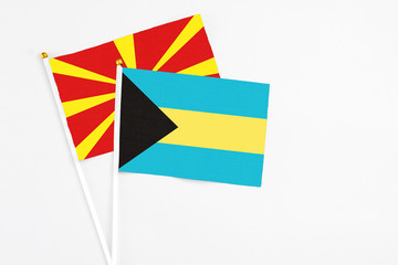 Bahamas and Macedonia stick flags on white background. High quality fabric, miniature national flag. Peaceful global concept.White floor for copy space.