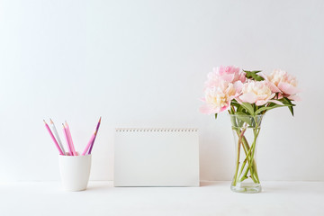 Mockup with a blank desk calendar and pink peonies in a vase on a white background