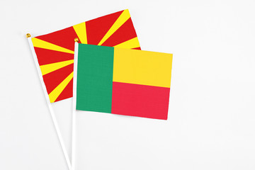 Benin and Macedonia stick flags on white background. High quality fabric, miniature national flag. Peaceful global concept.White floor for copy space.
