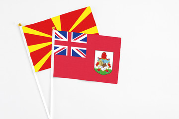 Bermuda and Macedonia stick flags on white background. High quality fabric, miniature national flag. Peaceful global concept.White floor for copy space.