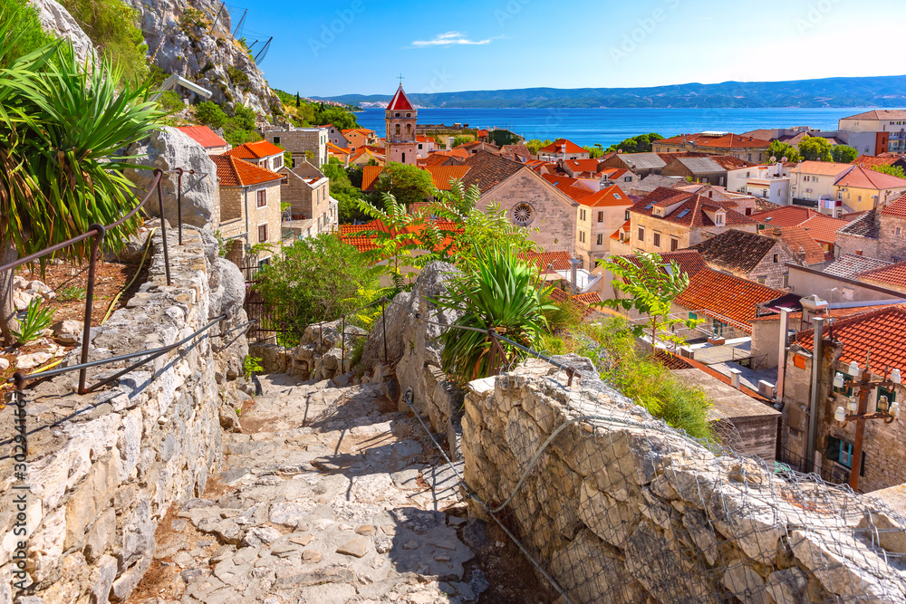 Wall mural sunny red roofs, old city street with stone stairs and church of st michael in town and port omis, p