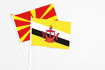 Brunei and Macedonia stick flags on white background. High quality fabric, miniature national flag. Peaceful global concept.White floor for copy space.
