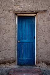 Fototapeta na wymiar Old blue door traditional adobe building in New Mexico USA. 
