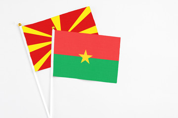 Burkina Faso and Macedonia stick flags on white background. High quality fabric, miniature national flag. Peaceful global concept.White floor for copy space.