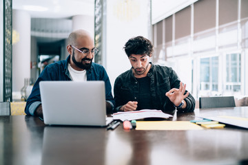 Stylish ethnic men coworking on project