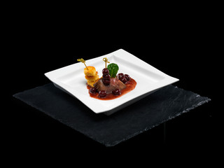 Assiette luxe viande de porc avec cerises et sauce isolé sur fond noir