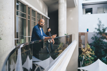 Contemporary smiling man with phone on balcony