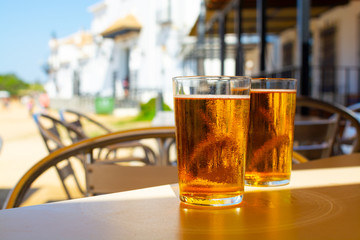 Cold amber color light spanish beer served in glass in outdoor cafe in town on sand, El Rocio in Andalusia, Spain