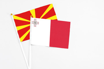 Malta and Macedonia stick flags on white background. High quality fabric, miniature national flag. Peaceful global concept.White floor for copy space.