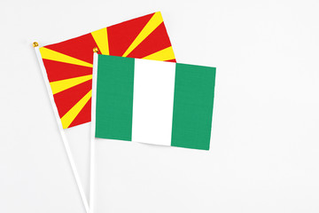 Nigeria and Macedonia stick flags on white background. High quality fabric, miniature national flag. Peaceful global concept.White floor for copy space.