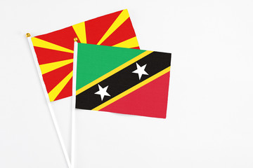 Saint Kitts And Nevis and Macedonia stick flags on white background. High quality fabric, miniature national flag. Peaceful global concept.White floor for copy space.