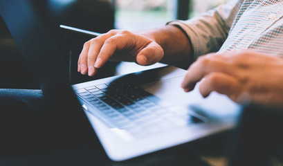 Close up view of male tattooed hands typing keyboarding email on laptop computer, cropped view with soft focus of internet user using technology for online communication. Online banking operations