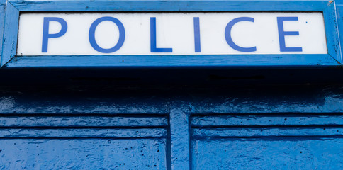 Obraz premium Police sign on top of old blue police box
