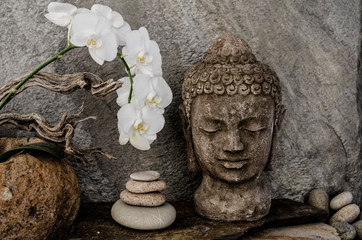 Buddha spa with balancing river stones and a white orchid flower.