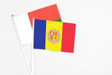 Andorra and Madagascar stick flags on white background. High quality fabric, miniature national flag. Peaceful global concept.White floor for copy space.