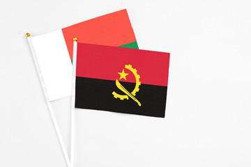 Angola and Madagascar stick flags on white background. High quality fabric, miniature national flag. Peaceful global concept.White floor for copy space.