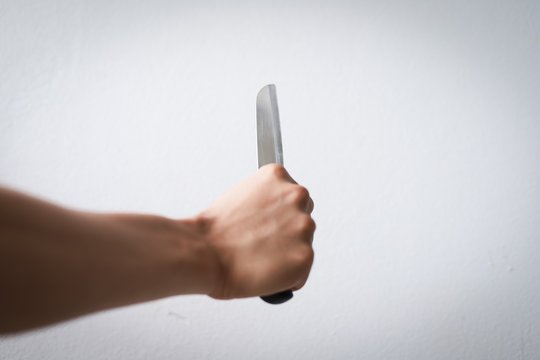 asian male hands are holding a knife to protect themselves from ananta or may be held to hurt others may be terrorists men hands tan skin in the hand with a knife background while textureand white 
