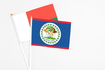 Belize and Madagascar stick flags on white background. High quality fabric, miniature national flag. Peaceful global concept.White floor for copy space.