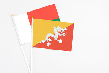 Bhutan and Madagascar stick flags on white background. High quality fabric, miniature national flag. Peaceful global concept.White floor for copy space.