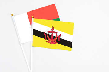 Brunei and Madagascar stick flags on white background. High quality fabric, miniature national flag. Peaceful global concept.White floor for copy space.