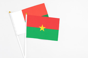 Burkina Faso and Madagascar stick flags on white background. High quality fabric, miniature national flag. Peaceful global concept.White floor for copy space.