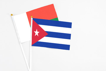 Cuba and Madagascar stick flags on white background. High quality fabric, miniature national flag. Peaceful global concept.White floor for copy space.