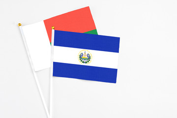 El Salvador and Madagascar stick flags on white background. High quality fabric, miniature national flag. Peaceful global concept.White floor for copy space.