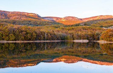 Autumn landscape of the lake at sunset. Lake and autumn forest in the mountains.