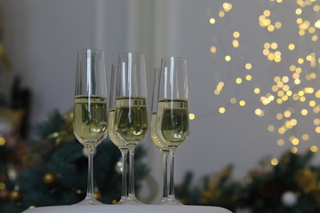 Six glasses for champagne and golden Christmas balls against a background of blurred golden lights. Celebrating New Year, Christmas or Birthday with glasses of champagne at party