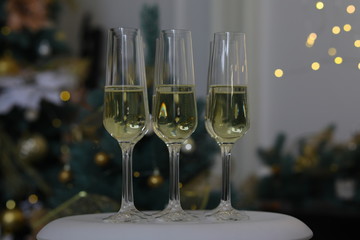 Six glasses for champagne and golden Christmas balls against a background of blurred golden lights. Celebrating New Year, Christmas or Birthday with glasses of champagne at party