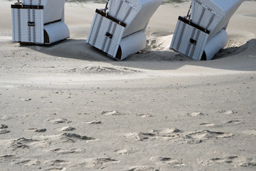 View on the bottom part of three white roofed wicker beach chairs standing insafely on the white...