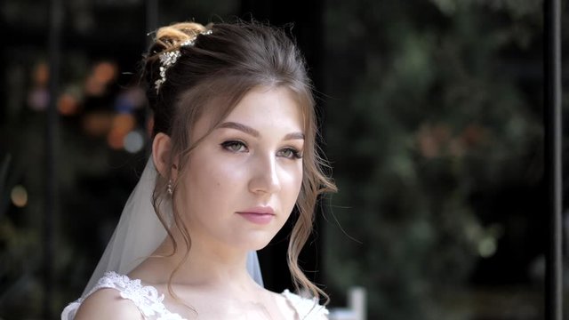 attractive dreaming young bride in lacy white dress poses in dark background at wedding party slow motion