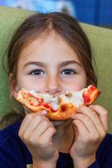 A child eats pizza with cheese and bacon