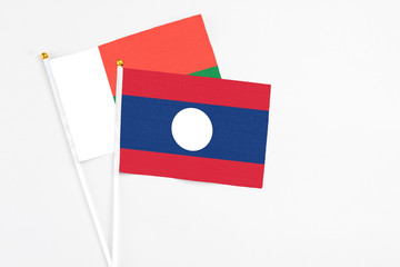 Laos and Madagascar stick flags on white background. High quality fabric, miniature national flag. Peaceful global concept.White floor for copy space.