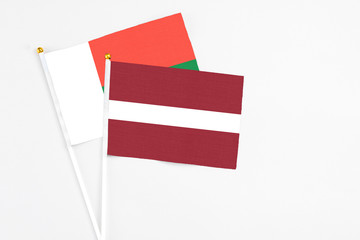 Latvia and Madagascar stick flags on white background. High quality fabric, miniature national flag. Peaceful global concept.White floor for copy space.