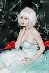 Fototapeta na wymiar Young glamour girl doll in white wig and blue dress posing alone