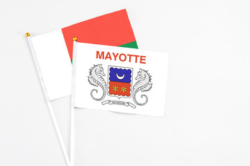 Mayotte and Madagascar stick flags on white background. High quality fabric, miniature national flag. Peaceful global concept.White floor for copy space.