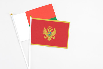 Montenegro and Madagascar stick flags on white background. High quality fabric, miniature national flag. Peaceful global concept.White floor for copy space.