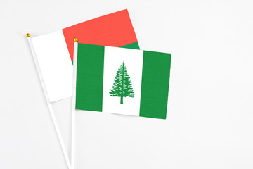 Norfolk Island and Madagascar stick flags on white background. High quality fabric, miniature national flag. Peaceful global concept.White floor for copy space.