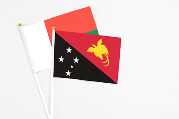 Papua New Guinea and Madagascar stick flags on white background. High quality fabric, miniature national flag. Peaceful global concept.White floor for copy space.