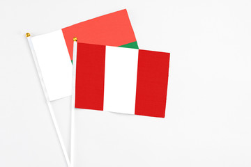 Peru and Madagascar stick flags on white background. High quality fabric, miniature national flag. Peaceful global concept.White floor for copy space.
