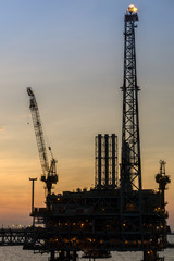 Fototapeta premium Silhouette of oil production platform during sunset