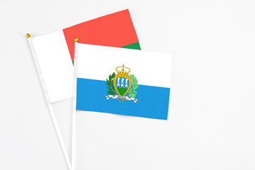 San Marino and Madagascar stick flags on white background. High quality fabric, miniature national flag. Peaceful global concept.White floor for copy space.